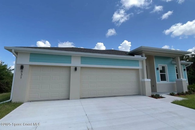 prairie-style house featuring concrete driveway, an attached garage, and stucco siding