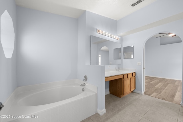 bathroom with a bath, visible vents, tile patterned floors, baseboards, and vanity