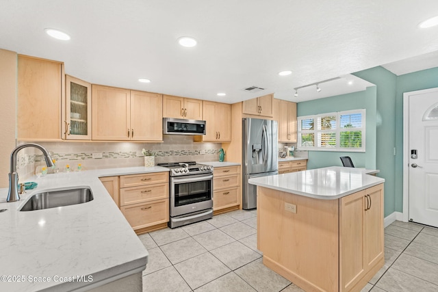 kitchen featuring appliances with stainless steel finishes, light brown cabinets, a sink, a kitchen island, and light tile patterned flooring