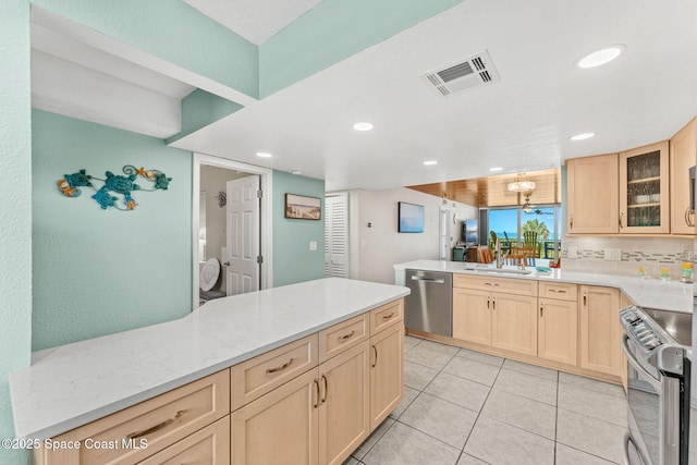 kitchen featuring stainless steel appliances, light brown cabinets, a sink, a peninsula, and glass insert cabinets