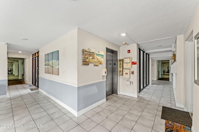 corridor with elevator, a textured ceiling, light tile patterned flooring, baseboards, and recessed lighting