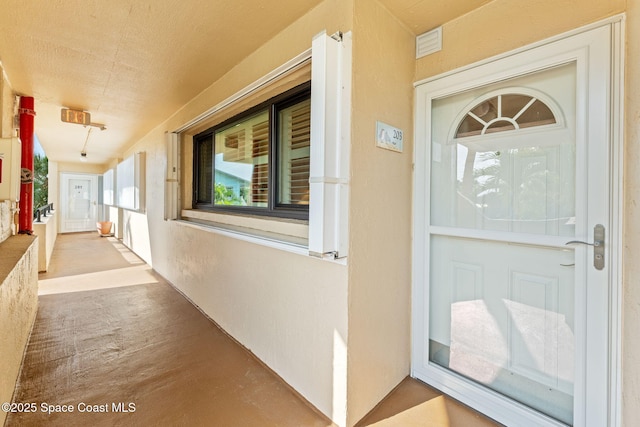 entrance to property with covered porch and stucco siding