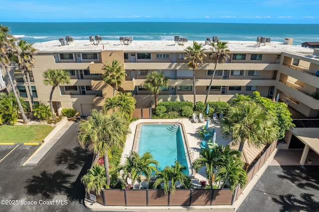 aerial view of a pool area, a nearby body of water, and apartment complex