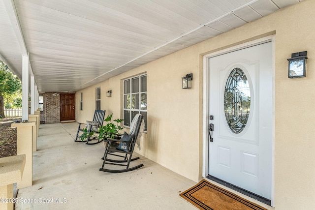 entrance to property featuring covered porch and stucco siding