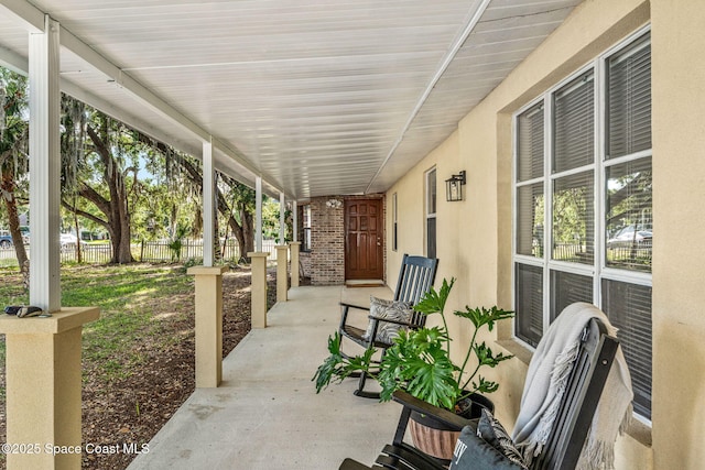 view of patio featuring a porch and fence
