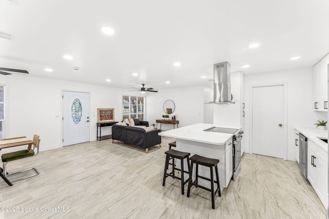 kitchen featuring a ceiling fan, island range hood, recessed lighting, white cabinets, and electric stove