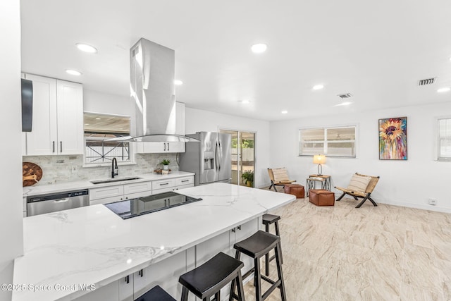 kitchen featuring a kitchen breakfast bar, white cabinets, a sink, backsplash, and stainless steel appliances