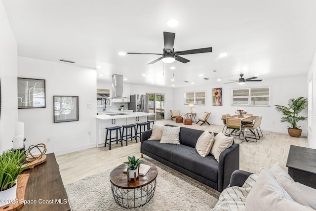 living room featuring recessed lighting, light wood finished floors, ceiling fan, and baseboards