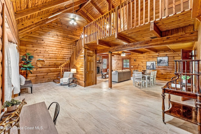 unfurnished living room featuring beamed ceiling, wood ceiling, ceiling fan, and rustic walls