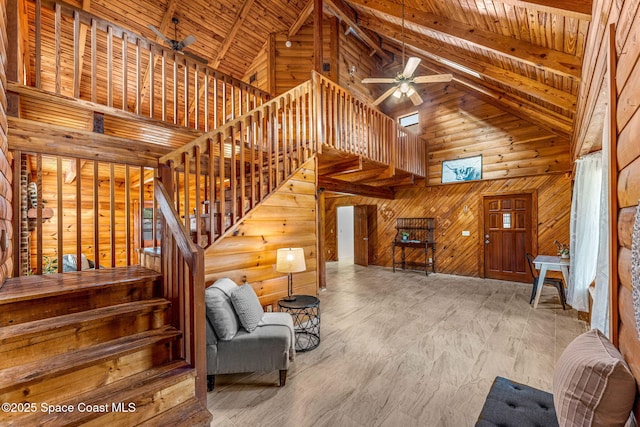 interior space with wooden walls, beam ceiling, high vaulted ceiling, a ceiling fan, and wood ceiling