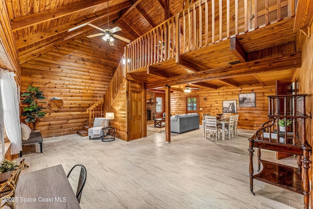 unfurnished living room featuring wooden ceiling, beamed ceiling, a ceiling fan, and log walls