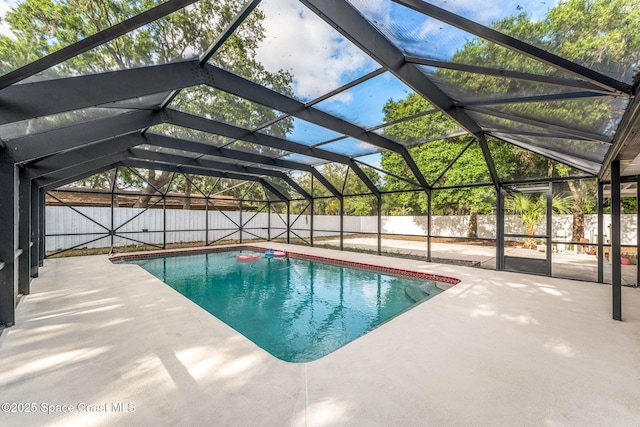 view of swimming pool with glass enclosure, a patio, a fenced in pool, and a fenced backyard
