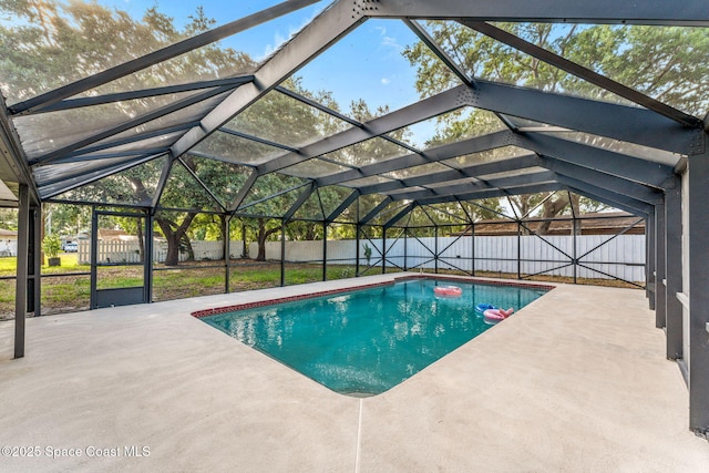 view of swimming pool featuring glass enclosure, a patio, a fenced in pool, and a fenced backyard