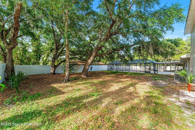 view of yard featuring a fenced backyard and glass enclosure