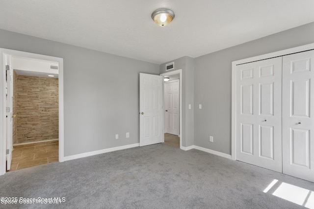 unfurnished bedroom with carpet flooring, ensuite bath, baseboards, visible vents, and a closet