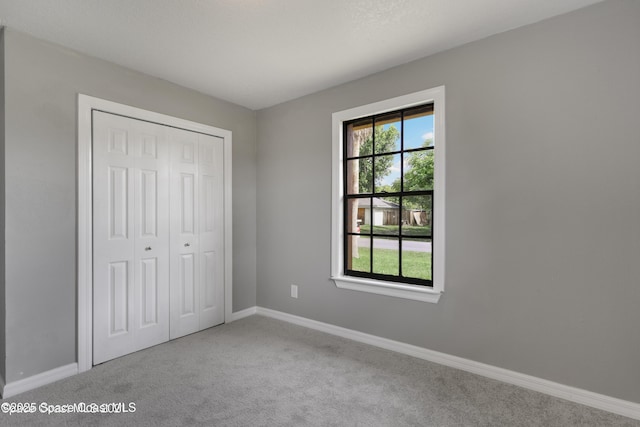 unfurnished bedroom featuring carpet floors, baseboards, and a closet
