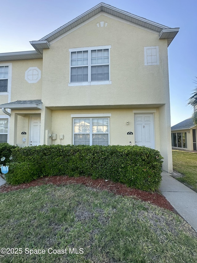 view of property featuring stucco siding and a front lawn