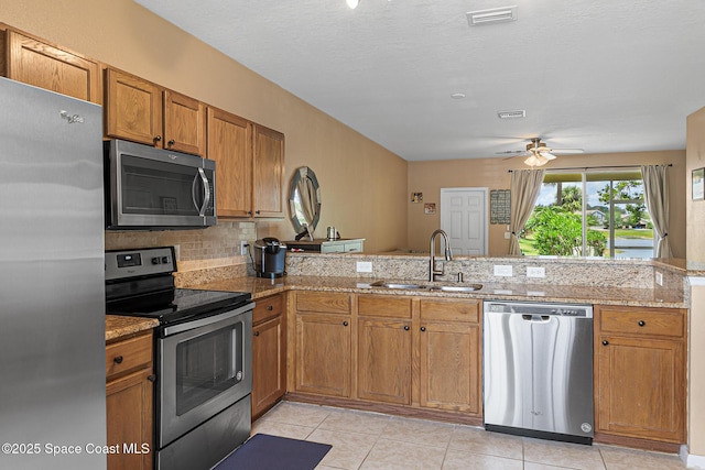 2990 S Fiske Blvd Unit C4, Rockledge, FL 32955 - kitchen featuring stainless steel appliances, a sink, brown cabinets, a ceiling fan, and a peninsula