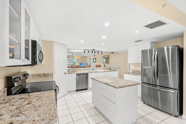 602 Shorewood Dr Unit A201, Cape Canaveral, FL 32920 - kitchen with stainless steel appliances, a peninsula, a kitchen island, a sink, and white cabinetry