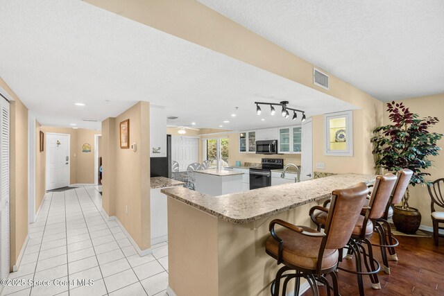 602 Shorewood Dr Unit A201, Cape Canaveral, FL 32920 - kitchen with appliances with stainless steel finishes, a sink, a peninsula, a kitchen bar, and white cabinets
