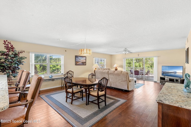 602 Shorewood Dr Unit A201, Cape Canaveral, FL 32920 - dining space with dark wood finished floors, a textured ceiling, a chandelier, a ceiling fan, and baseboards