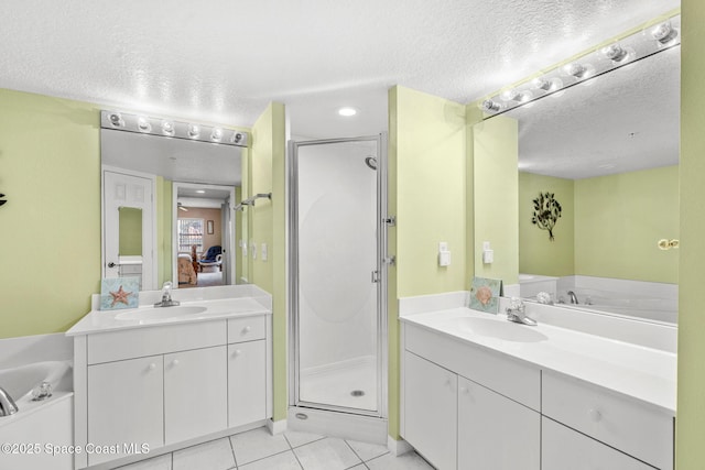 602 Shorewood Dr Unit A201, Cape Canaveral, FL 32920 - ensuite bathroom with a textured ceiling, a stall shower, tile patterned flooring, two vanities, and a garden tub