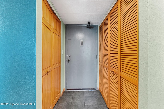 hall with a textured wall and tile patterned floors