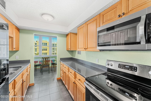kitchen featuring appliances with stainless steel finishes, a textured ceiling, light tile patterned floors, baseboards, and dark countertops