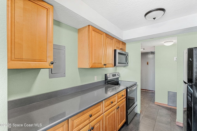 kitchen with appliances with stainless steel finishes, a textured ceiling, electric panel, dark countertops, and tile patterned floors