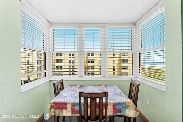 dining area with a textured wall, a textured ceiling, and baseboards