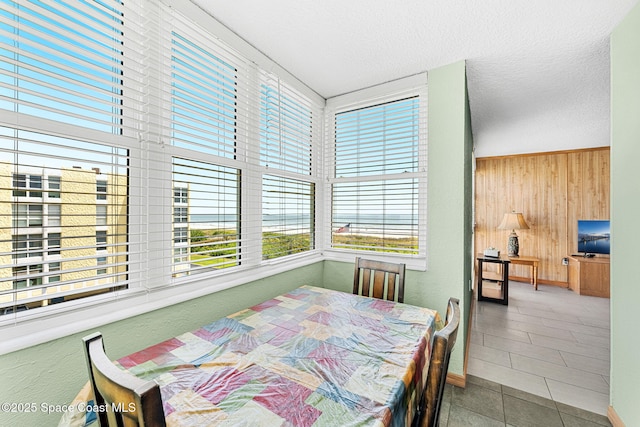 dining space with wooden walls and tile patterned floors