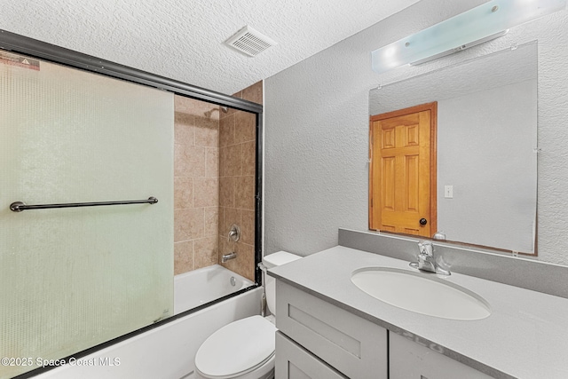bathroom with a textured wall, toilet, combined bath / shower with glass door, vanity, and a textured ceiling