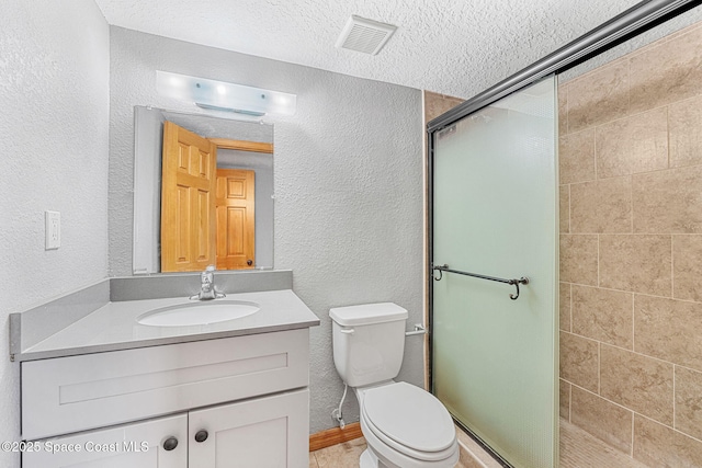 full bath with a textured wall, a shower stall, vanity, toilet, and a textured ceiling