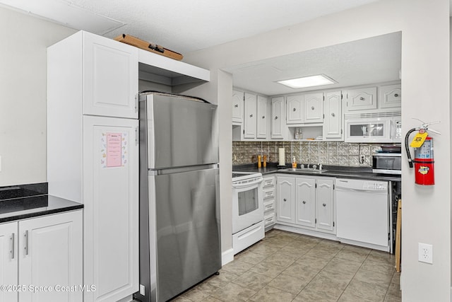 kitchen with stainless steel appliances, dark countertops, white cabinets, and a textured ceiling