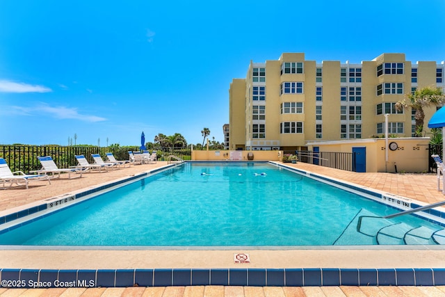 community pool featuring fence and a patio