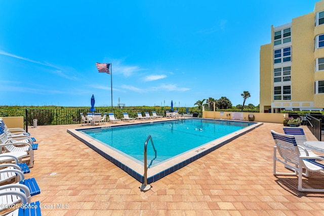 community pool with a patio and fence