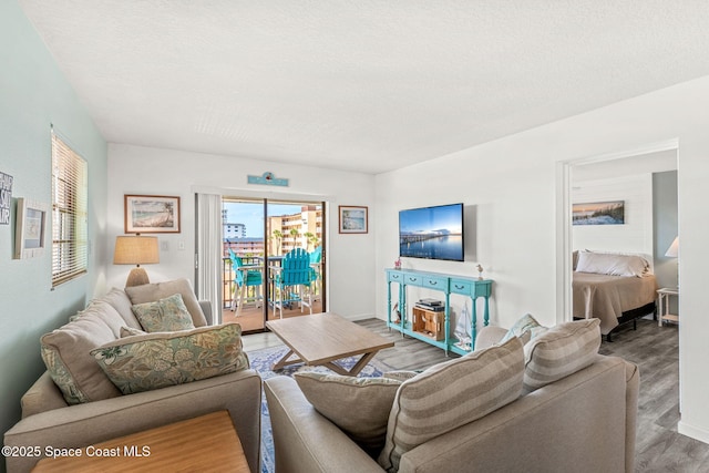 living room with baseboards, a textured ceiling, and wood finished floors