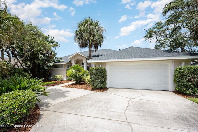 ranch-style house featuring a shingled roof, stucco siding, and concrete driveway