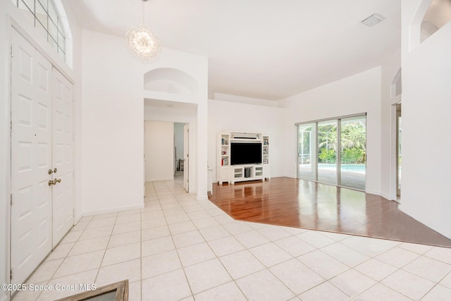 unfurnished living room featuring visible vents, baseboards, light tile patterned flooring, and a notable chandelier