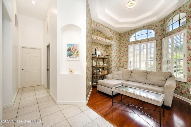 sitting room with light tile patterned floors, wallpapered walls, baseboards, and a raised ceiling
