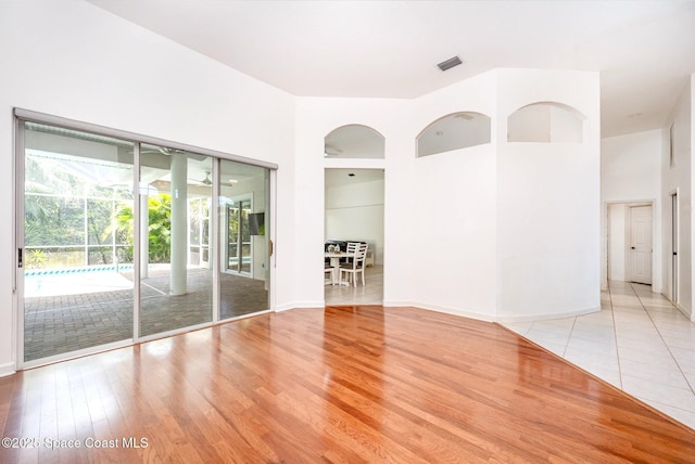 unfurnished room with baseboards, wood finished floors, and visible vents