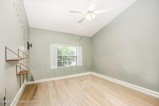 empty room with baseboards, ceiling fan, wood finished floors, and lofted ceiling