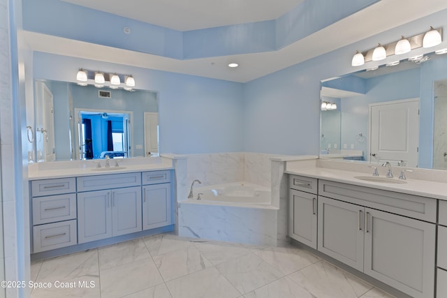 bathroom featuring marble look tile flooring, two vanities, a bath, and recessed lighting