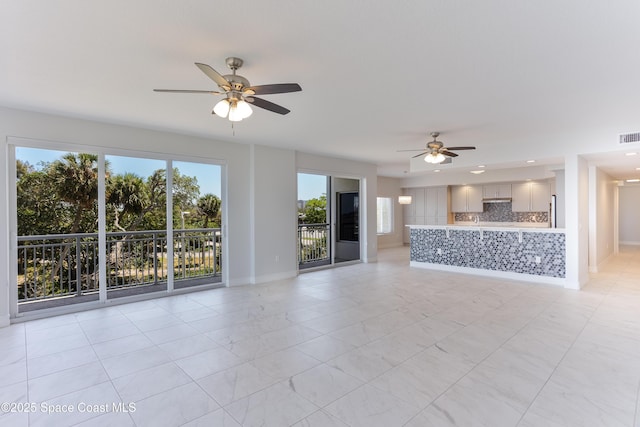 unfurnished living room with a ceiling fan and baseboards