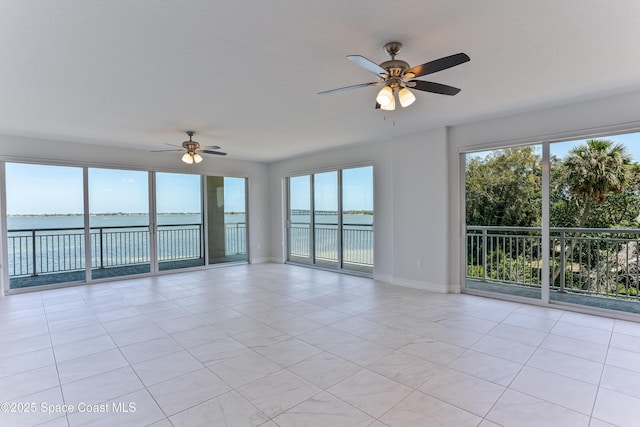spare room featuring ceiling fan, a water view, baseboards, and light tile patterned floors