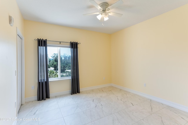 empty room featuring a ceiling fan, baseboards, and light marble finish floors