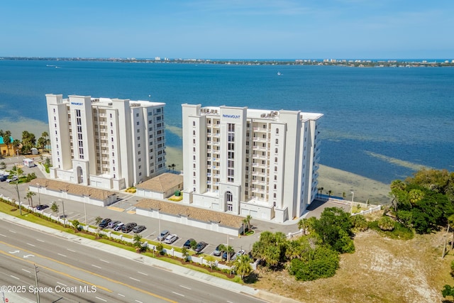 drone / aerial view of a nearby body of water and apartment complex / building
