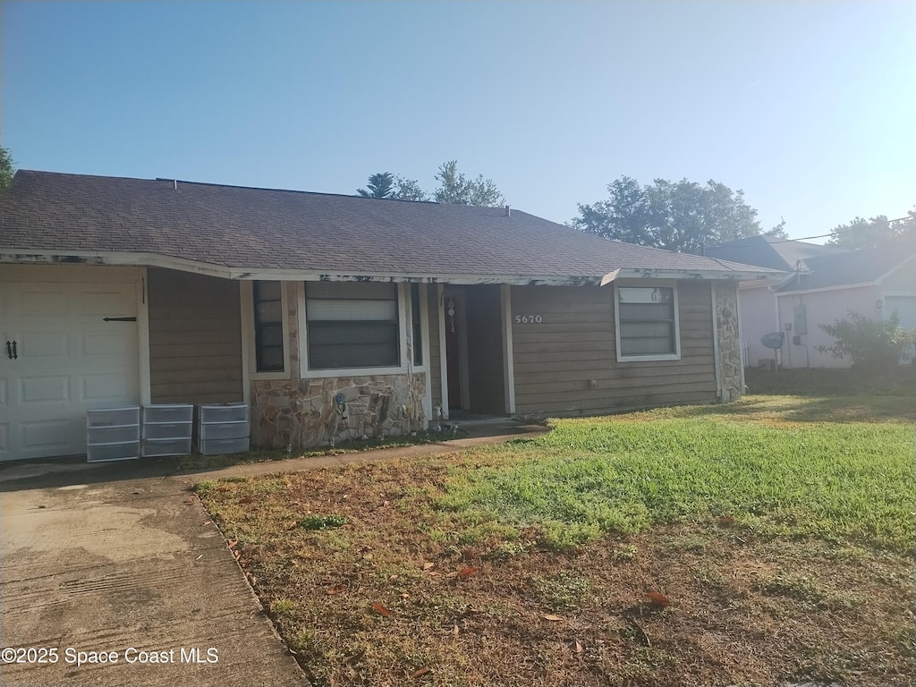 ranch-style house with a front lawn, driveway, roof with shingles, and an attached garage