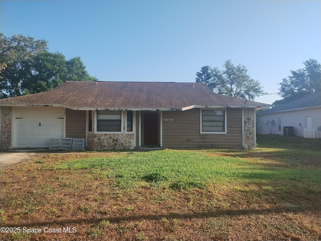 ranch-style home featuring stone siding, a garage, central AC, a front yard, and driveway