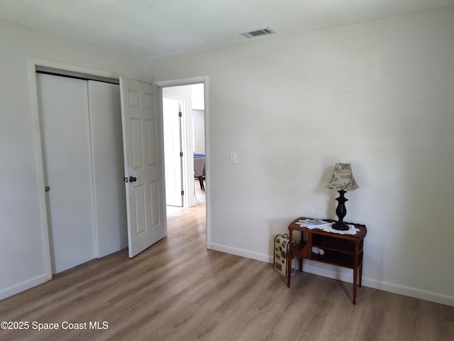 bedroom featuring baseboards, a closet, light wood-type flooring, and visible vents